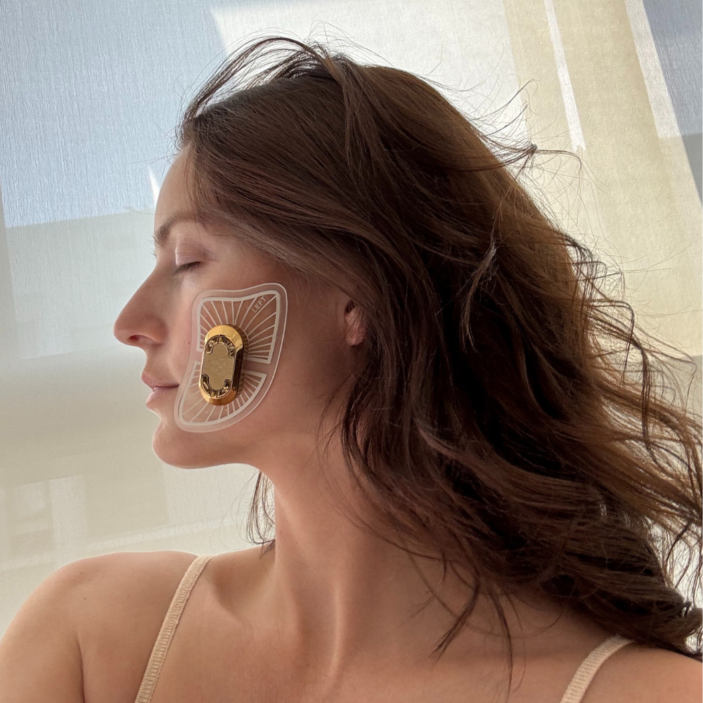 Woman using EMS device for face lifting at home